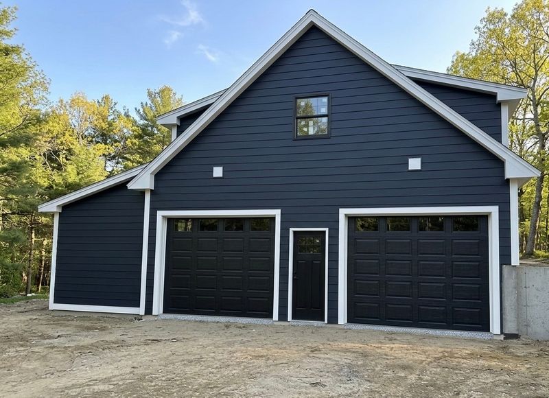 Navy blue new construction garage with black dual doors and white trim